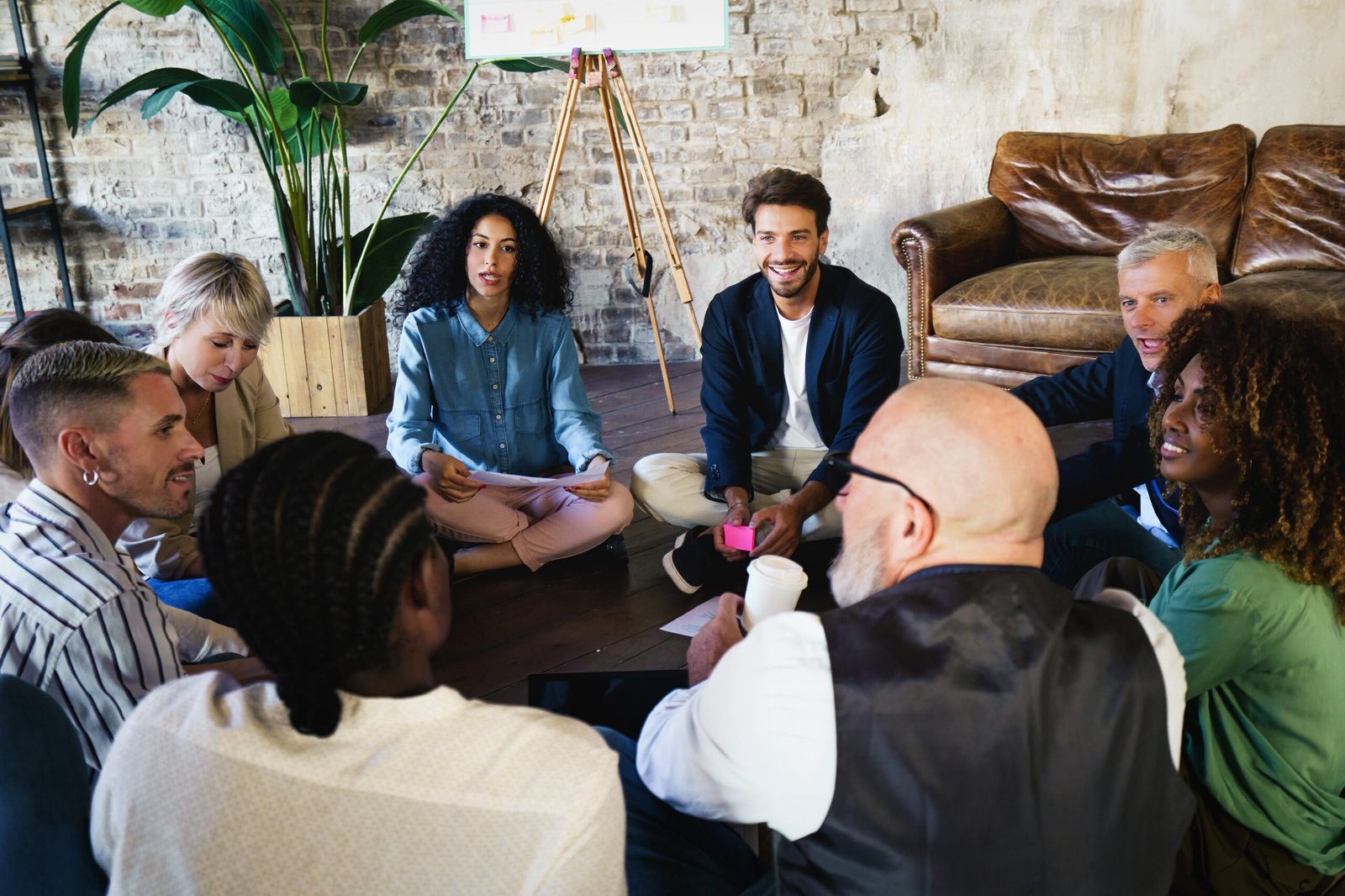 A diverse group of professionals sitting in a circle and talking together, representing open dialogue and relationship repair.