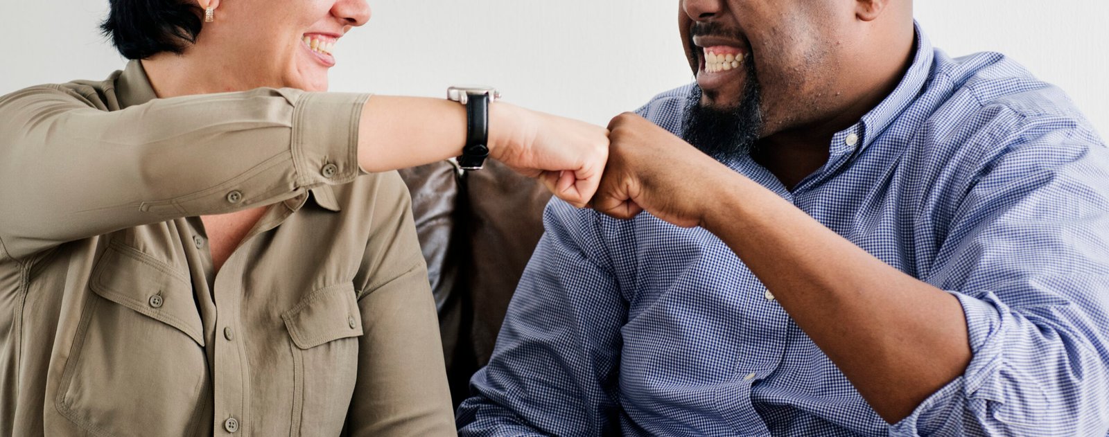 Two coworkers smiling and bumping fists, representing positive rapport and mutual respect at work.