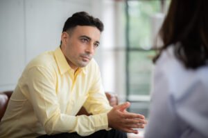 A man leaning forward and listening attentively during a conversation, representing active listening and thoughtful communication.