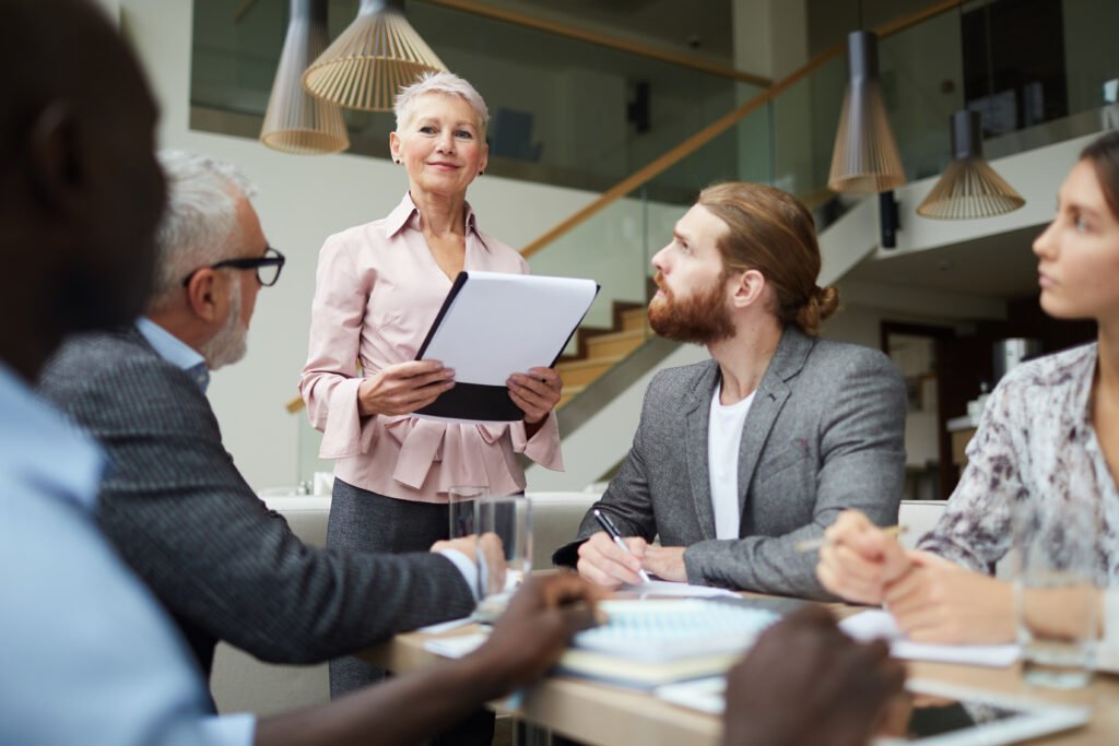 A professional leader presenting information to a group during a meeting, representing strategic guidance and organizational alignment.