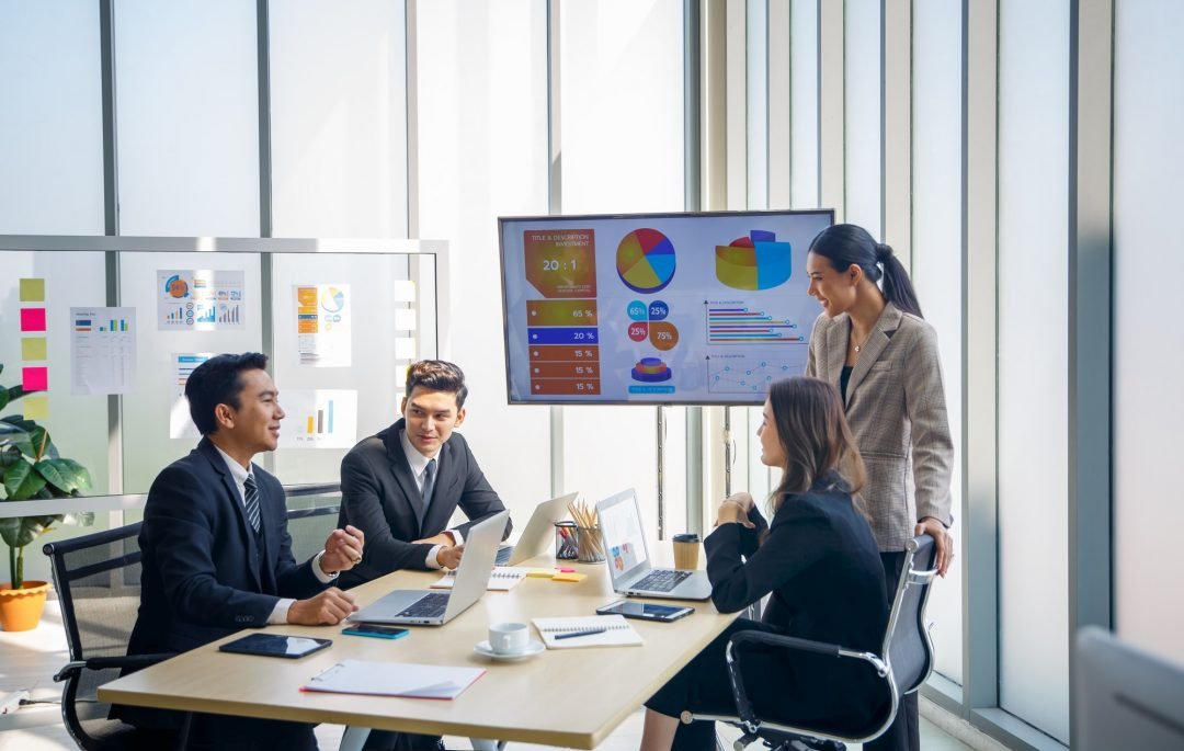 A group of professionals discussing information together during a meeting, representing guidance and collaboration during organizational change.