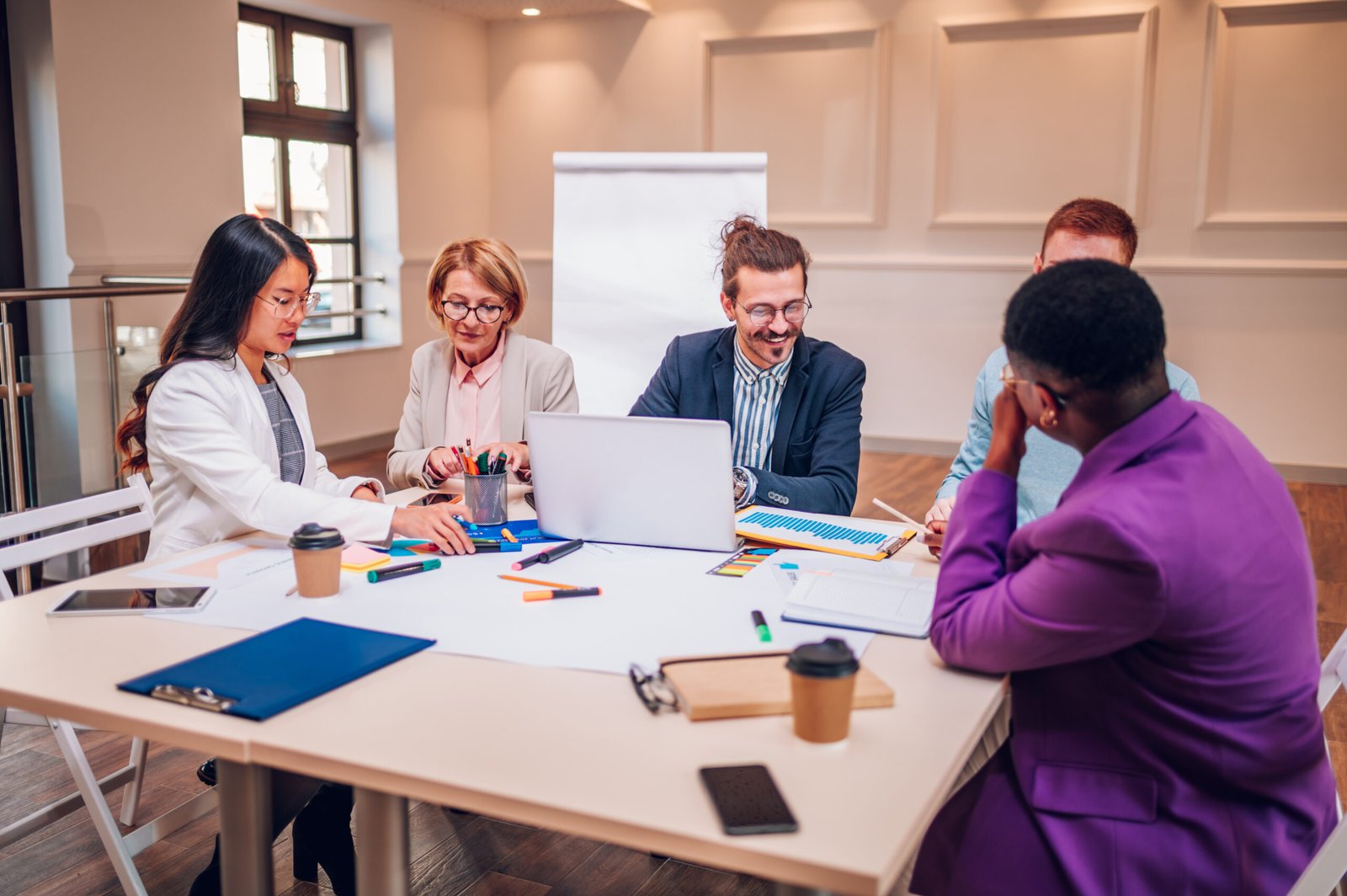 A group of professionals working together at a table, representing employee empowerment through collaboration and guided problem-solving.